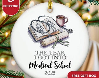 May include: A white ceramic ornament with a gold string for hanging. The ornament features medical school-themed illustrations, including a book with anatomical drawings, a stethoscope, and a diploma. Text reads "THE YEAR I GOT INTO Medical School 2025."