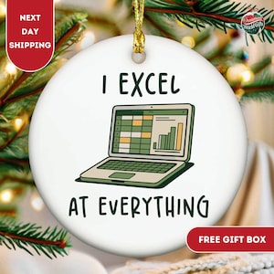 May include: White ceramic Christmas ornament with the text "I EXCEL AT EVERYTHING" and a laptop graphic displaying a spreadsheet and bar graph. The ornament has a gold string for hanging and is surrounded by greenery.