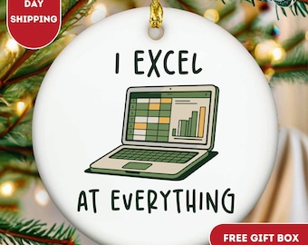 May include: White ceramic Christmas ornament with the text "I EXCEL AT EVERYTHING" and a laptop graphic displaying a spreadsheet and bar graph. The ornament has a gold string for hanging and is surrounded by greenery.