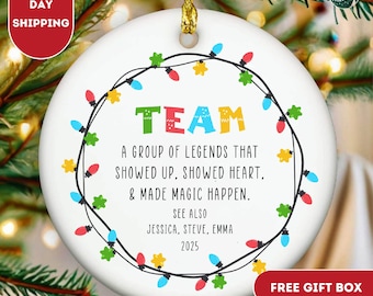 May include: A white ceramic Christmas ornament with the word "TEAM" in colorful letters, surrounded by a string of colorful lights. The text reads "A group of legends that showed up, showed heart, & made magic happen."
