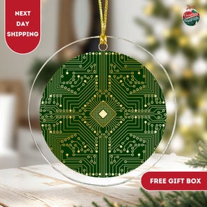 May include: A round, clear glass Christmas ornament with a green and gold circuit board design. The ornament is hanging from a gold string.
