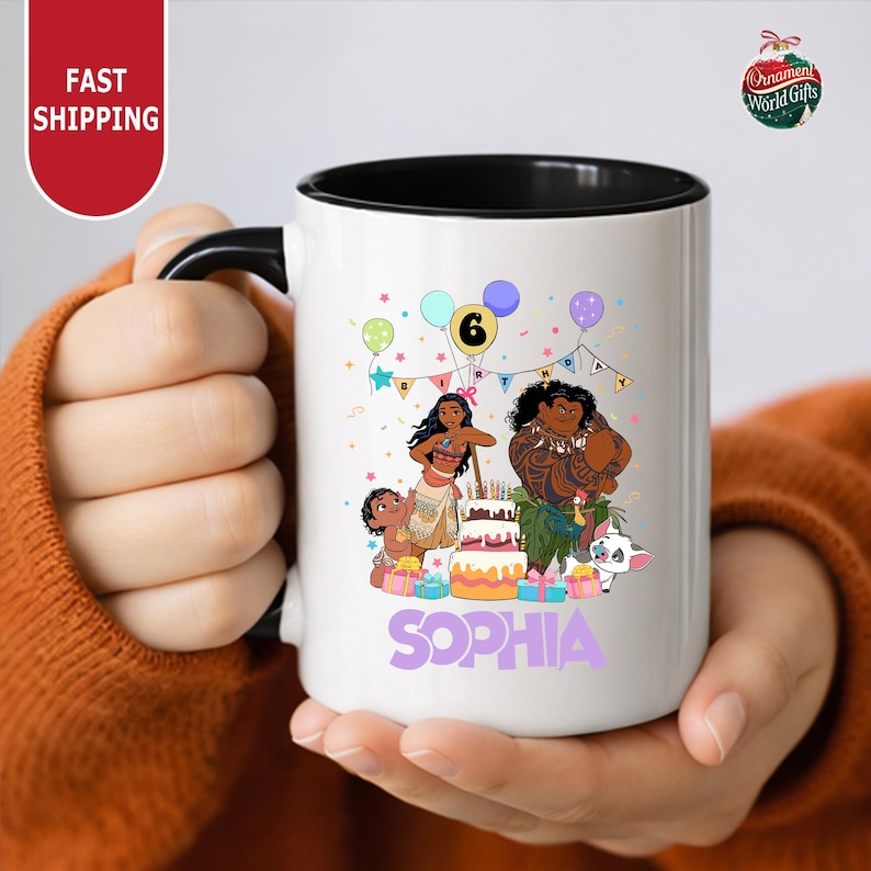 A person is holding a white mug with a colorful illustration of characters from the movie "Moana" and the text "Sophia" on it.