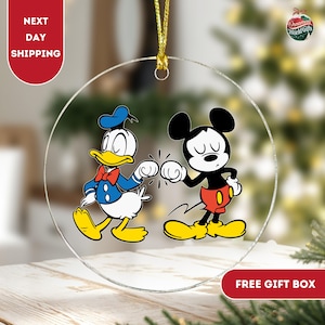 May include: A round glass bauble featuring a cartoon image of Mickey Mouse and Donald Duck giving each other a high five. The background is clear.