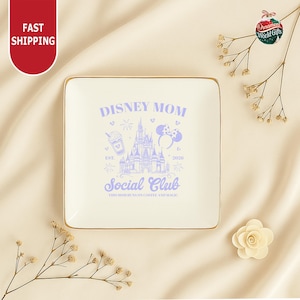 a white plate with a Disney-themed design, surrounded by decorative elements such as dried flowers and branches.