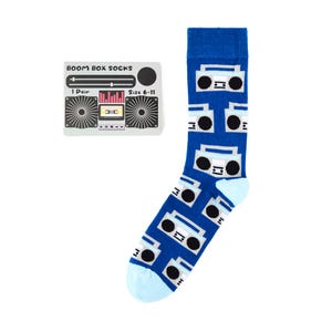 May include: A pair of blue socks with a white and black boombox pattern. The socks are size 6-11 and come with a card that says "Boom Box Socks" and has a picture of a boombox.