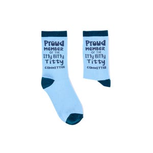 Op de afbeelding: Een paar lichtblauwe sokken met donkerblauwe accenten op de tenen, hiel en boord. De sokken tonen de tekst "Proud Member of the Itty Bitty Titty Committee" in donkerblauw.