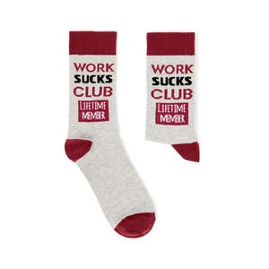 May include: A pair of light grey crew socks featuring a dark red cuff, heel, and toe. The text WORK SUCKS CLUB is printed in dark red and black, with a dark red rectangular box containing the white text LIFETIME MEMBER below the main phrase.