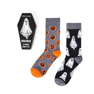 May include: Two pairs of Halloween socks. One pair is grey with orange jack-o'-lanterns, and the other is black with white ghosts. The socks are displayed with a black coffin-shaped box that reads "Urban Eccentric" and "Socks 2 Pairs Size 6-11".