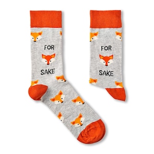 May include: A pair of grey socks with orange fox faces and the text "FOR SAKE" printed on them. The socks have an orange cuff.
