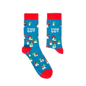 May include: A pair of blue socks with a red cuff and a white mushroom pattern. The socks have the text "FUN GUY" printed on them.