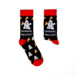 May include: A pair of black socks with red cuffs and toes. The socks feature a repeating pattern of white ghosts and pizza slices. The words "PARANORMAL SNACKTIVITY" are printed on the front of each sock.