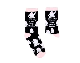 Puede incluir: Calcetines negros con puños, talones y punteras rosas. Presentan ilustraciones de fantasmas blancos y el texto "Eternally in love with Spooky Season". Ideales para Halloween.