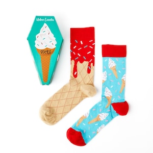 May include: A pair of novelty socks with an ice cream cone design. One sock features a red ice cream cone with sprinkles, and the other sock features a blue ice cream cone with sprinkles. The socks come in a box with a picture of an ice cream cone and the words "Urban Eccentric Socks".