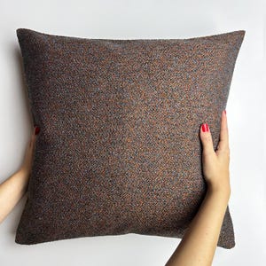 May include: A brown and gray throw pillow with a textured fabric.