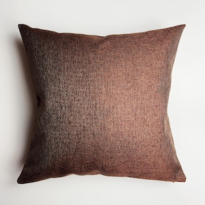 May include: A brown square throw pillow with a textured fabric.