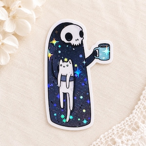 Könnte beinhalten: Ein gestanzter Aufkleber mit einer dunklen, sternenbedeckten Sensenmann-Figur mit weißem Totenkopfgesicht. Die Figur hält eine hellblaue Tasse und trägt eine kleine, weiße Katze vor der Brust. Das Design enthält holografische Sternakzente.