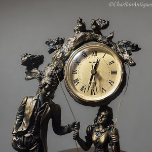 Puede incluir: Un reloj de bronce con un diseño de árbol y dos figuras. La esfera del reloj es dorada con números romanos negros y manecillas. El reloj dice "Decapeo Quartz".