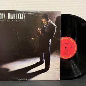 以下が含まれることがあります： トランペットを演奏するミュージシャンが描かれたWynton Marsalisのアルバム「Hot House Flowers」のレコードジャケットと、数字の2と黒い文字でトラックリストが印刷された赤いコロンビアレーベルが付いた黒いレコード盤。