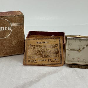 May include: A white ceramic mug with a black handle and the text "But First, Coffee" in a handwritten style. The mug is on a white surface. The mug is likely for hot beverages.