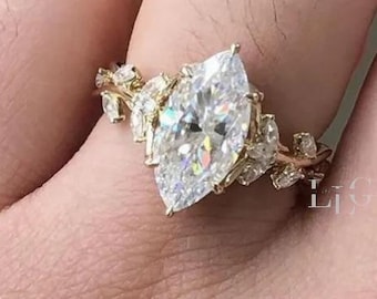 May include: A gold ring with a large, marquise-cut diamond at its centre. The band is embellished with smaller diamonds and leaf-like features, creating an elegant, nature-inspired design. The ring is a beautiful piece of jewellery.