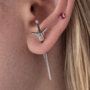 May include: A white ceramic mug with a black handle and the text "But First, Coffee" in a black, bold font. The mug is on a white surface.