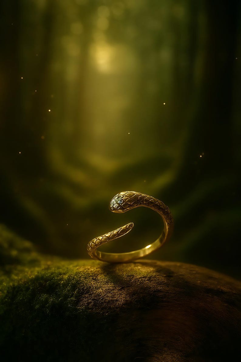 May include: A gold-colored snake ring with a textured pattern. The snake's head features a small, clear gemstone. The ring is set against a blurred, green forest background, creating a mystical aesthetic.