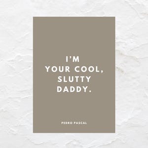 Puede incluir: Impresión rectangular con el texto "I'M YOUR COOL, SLUTTY DADDY." en blanco sobre un fondo color topo. El nombre "PEDRO PASCAL" está impreso debajo en blanco. El fondo es una superficie blanca texturizada.