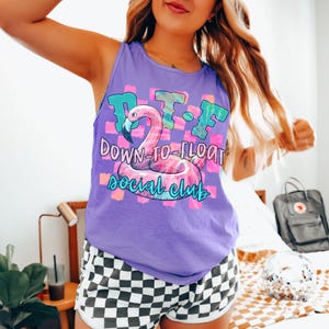 May include: Purple tank top with a graphic of a pink flamingo pool float and the text "D.T.F. Down-to-Float Social Club".