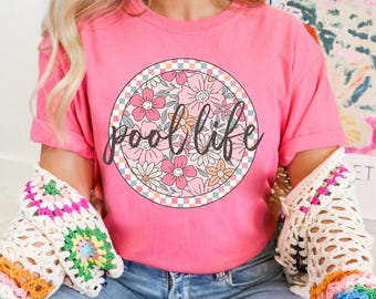 May include: Pink t-shirt with a floral design and the text "pool life" in a circle.