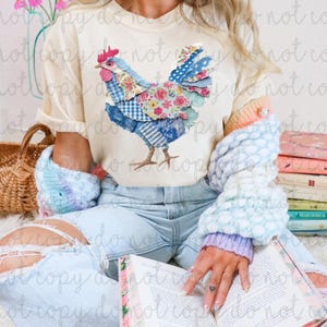 Könnte beinhalten: Cremefarbenes T-Shirt mit einem Patchwork-Hühnerdesign in Blau-, Rosa- und Blumenmustern. Das Huhn hat einen roten Kamm. Teil einer lässigen Bekleidungskollektion.
