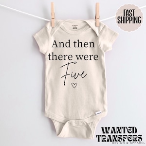 May include: A white baby onesie with black text that reads "And then there were Five" with a small heart symbol.