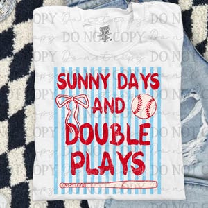May include: White t-shirt with the text "SUNNY DAYS AND DOUBLE PLAYS" in red, with a baseball, bow, and bat graphic. The shirt has blue vertical stripes.