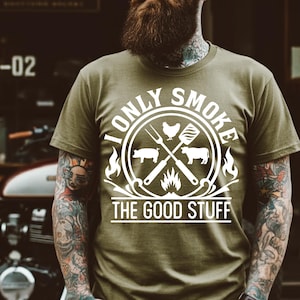 May include: A green t-shirt with a white graphic design. The graphic features a circle with the text "I Only Smoke The Good Stuff" and a crossed set of grilling tools with a pig, cow, and chicken.