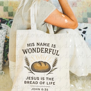 May include: Cream-colored tote bag with the text "HIS NAME IS WONDERFUL" above an illustration of a loaf of bread and wheat stalks. Below the illustration, the text reads "JESUS IS THE BREAD OF LIFE" and "JOHN 6:35".