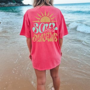 May include: A pink t-shirt with a retro-style graphic design featuring a sun and the text "Soul full of sunshine".