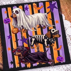 Puede incluir: Un estampado gráfico cuadrado con tres perros salchicha con disfraces de Halloween sobre un fondo de rayas verticales negras, naranjas y moradas. Los perros están vestidos de fantasma, esqueleto con gorro de calavera y vampiro con capa.
