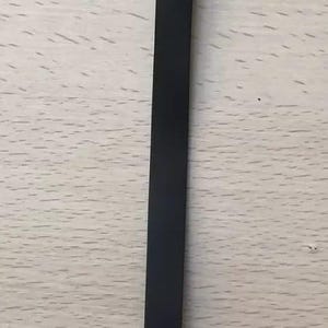 May include: A black metal strap with a buckle and a hole at each end. The strap is long and narrow, and appears to be a component of a larger item. The background is a light wood grain.