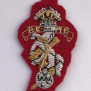 May include: A red felt embroidered patch with a gold crown, a silver and gold anchor, and the text "RE-GIMENT" in gold.