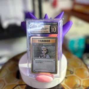 May include: A Pokemon trading card featuring a Trainer card with a picture of Professor Oak. The card is graded a 10 by a third-party grading company. The card is in a protective case.