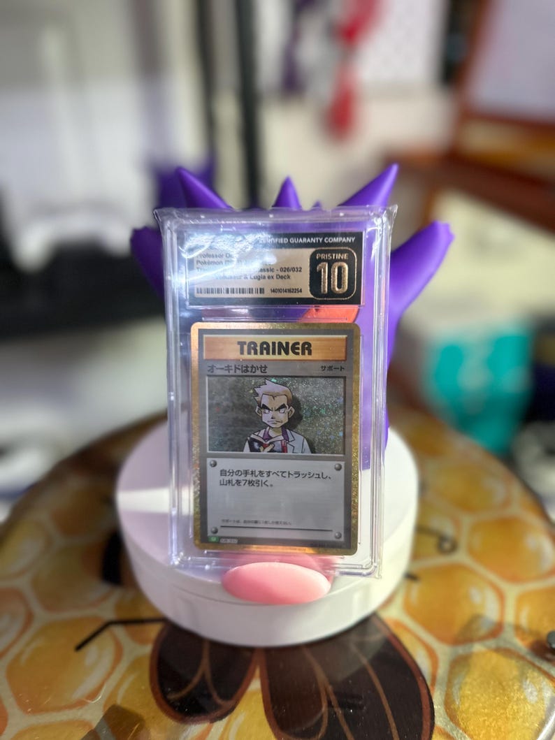 May include: A Pokemon trading card featuring a Trainer card with a picture of Professor Oak. The card is graded a 10 by a third-party grading company. The card is in a protective case.