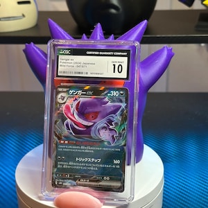 May include: A graded Pokemon trading card featuring Gengar ex from the Wild Force set. The card is in Gem Mint condition and has a grade of 10. The card is in a clear plastic case with a white label that says "Certified Guaranty Company".