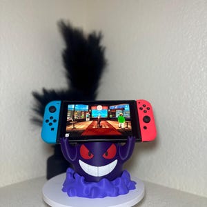 May include: A white ceramic mug with a black handle and the text "But First, Coffee" in a bold, black font. The mug is set against a blurred background, suggesting a cozy setting. The mug appears to be approximately 4 inches tall.