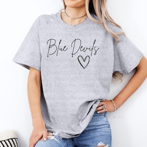 May include: A heather gray t-shirt with the text "Blue Devils" in a handwritten font and a heart symbol. The shirt is a casual style, with short sleeves.