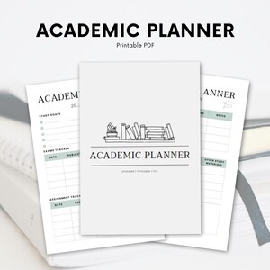 Op de afbeelding: Een printbare academische planner in grijs en wit. De omslag heeft een stapel boeken met een afstudeerhoed er bovenop. De tekst "ACADEMIC PLANNER" is in zwart op de omslag gedrukt.
