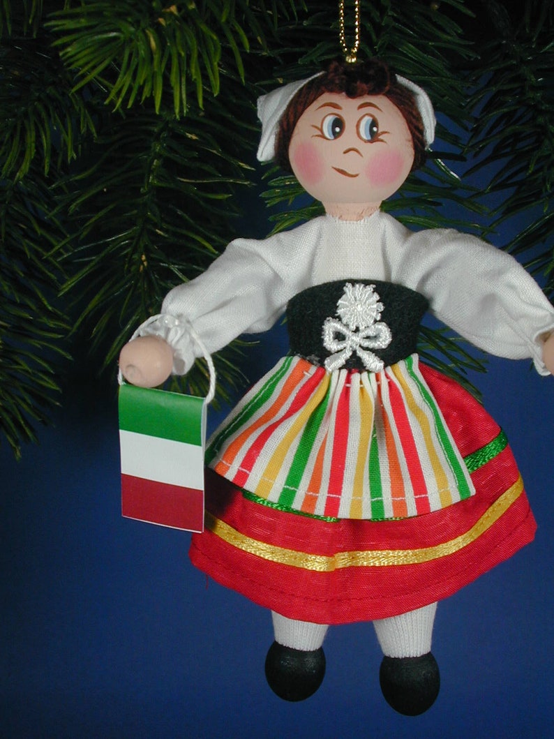 May include: A handmade Christmas ornament depicting a girl wearing a traditional Italian dress with a red, white, and green striped skirt and a green, white, and red flag.