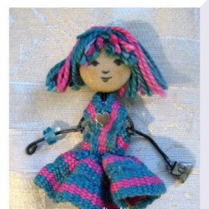 May include: A handmade doll with blue and pink yarn hair, a blue and pink striped dress, and blue shoes. The doll is made with wire and has a wooden head with painted features.