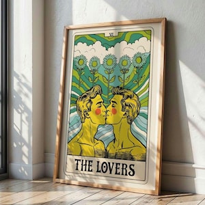 Peut inclure: Une illustration de carte de tarot de style vintage de la carte des Amoureux, représentant deux hommes s'embrassant devant un fond vert et bleu avec cinq fleurs jaunes. La carte est encadrée dans un cadre en bois.
