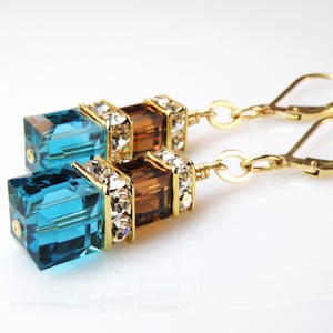 crystal dangle earrings with small chocolate brown cube on top of a larger deep teal blue cube with rhinestone crowns on top and set on gold leverbacks