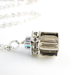 May include: A silver chain necklace with a pendant featuring a faceted smoky quartz stone surrounded by clear rhinestones.