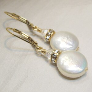 May include: Gold tone earrings with a white pearl and crystal accents.
